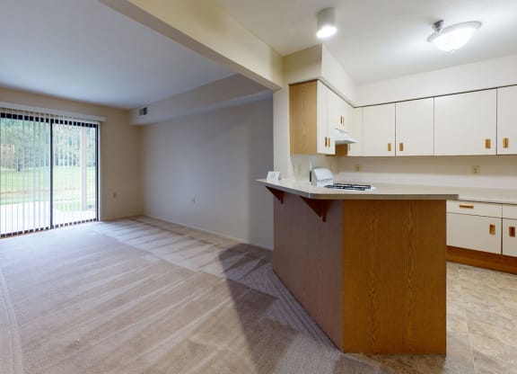 an empty living room and kitchen with a sliding glass door at Trillium Pointe Apartment Homes, Jackson, MI