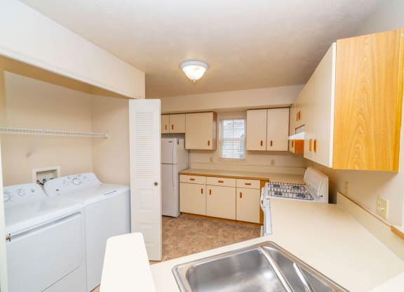 a kitchen with a washer and dryer and a sink at Trillium Pointe Apartment Homes, Jackson, Michigan
