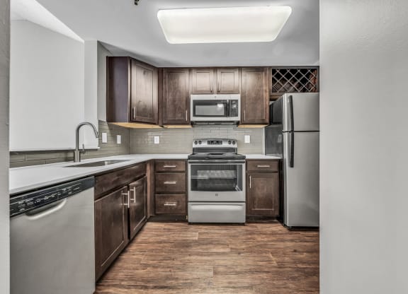 an empty kitchen with stainless steel appliances and wooden cabinets at Trophy Club at Bellgrade, Midlothian, VA, 23113