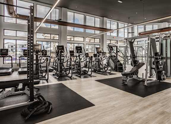 A gym with a variety of equipment including treadmills, weights, and exercise machines.