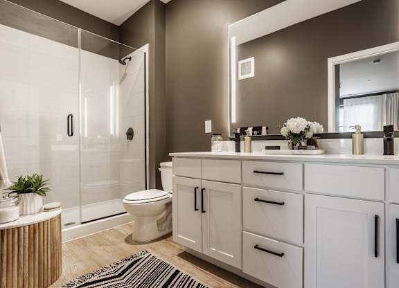 A modern bathroom with a glass shower, white cabinetry, and a large mirror at Upper Vue Flats, Dublin