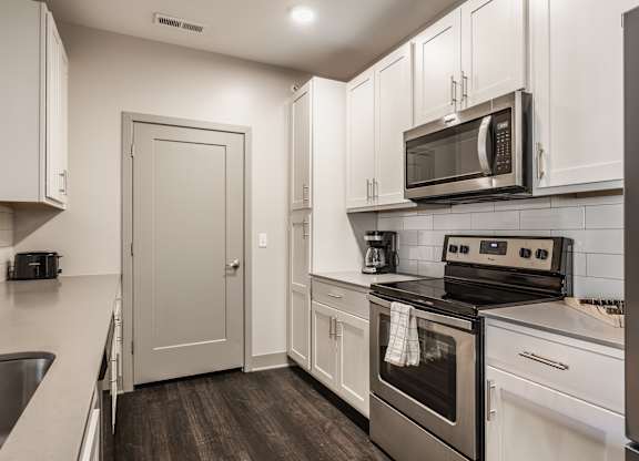 A kitchen with white cabinets and a black stove top oven.