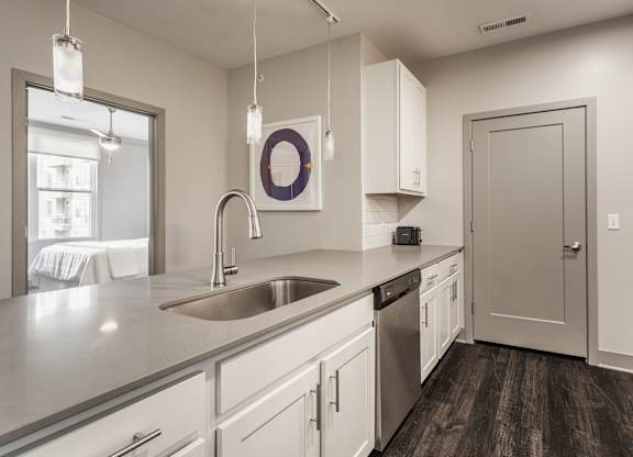 A kitchen with white cabinets and a wooden floor.