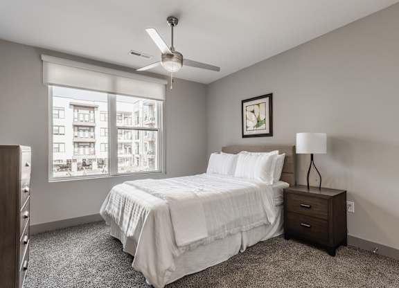 A bedroom with a bed, nightstand, and window.