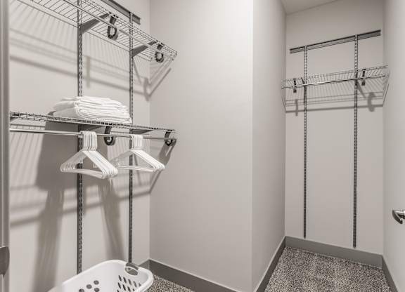 A laundry room with a white door and a metal rack with clothes hanging on it.