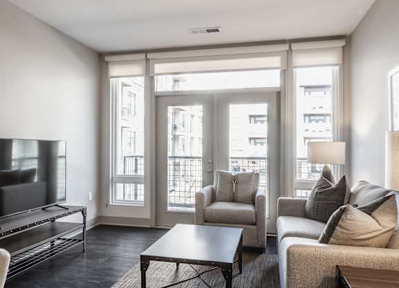 A living room with a television, couch, and chairs.