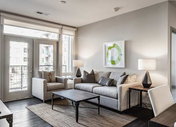 A modern living room with a grey sofa, a coffee table, and a painting on the wall.