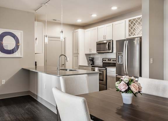 A modern kitchen with a wooden table and a vase of flowers.