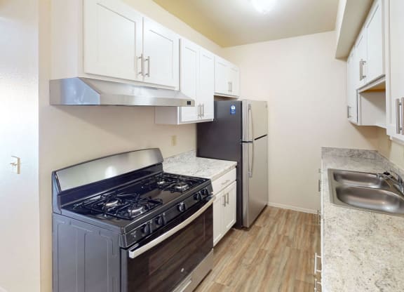 a renovated kitchen with stainless steel appliances and white cabinets at Walnut Trail Apartments in Portage, MI 49002