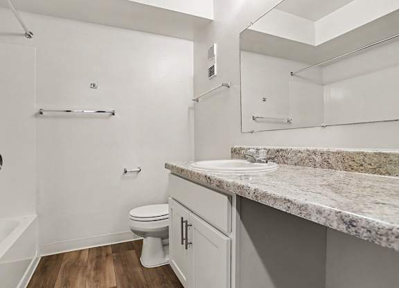 A white bathroom with a large counter top and a toilet at Walnut Trail Apartments, Michigan