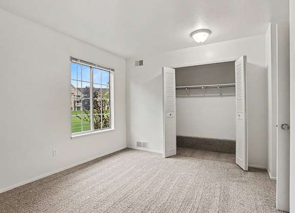 A spacious bedroom with a large window and a closet at Walnut Trail Apartments, Michigan