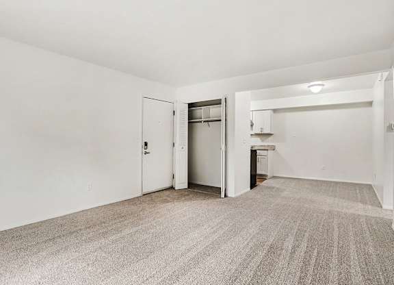 A living and dining room with a carpeted floor and a closet at Walnut Trail Apartments, Michigan