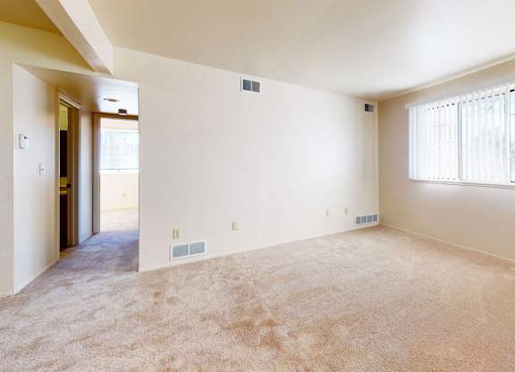 A large garden style living room with a window and carpeted floor at Walnut Trail Apartments, Michigan