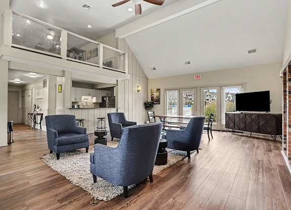 A community building with blue chairs and plank floor at Walnut Trail Apartments, Michigan