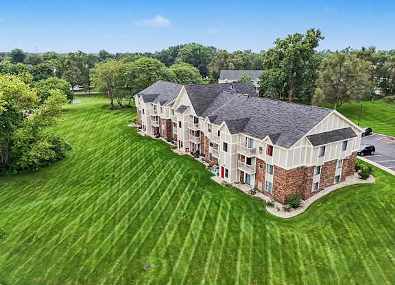 A large building with a green lawn in front of it at Walnut Trail Apartments, Michigan