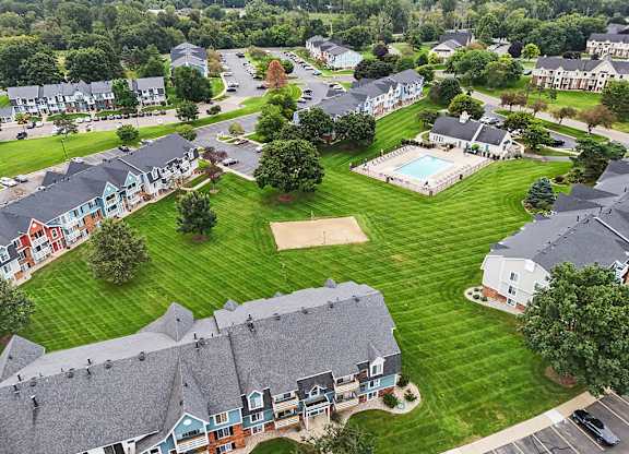 A bird's eye view of a residential area with apartment buildings, a swimming pool, and a parking lot at Walnut Trail Apartments, Michigan