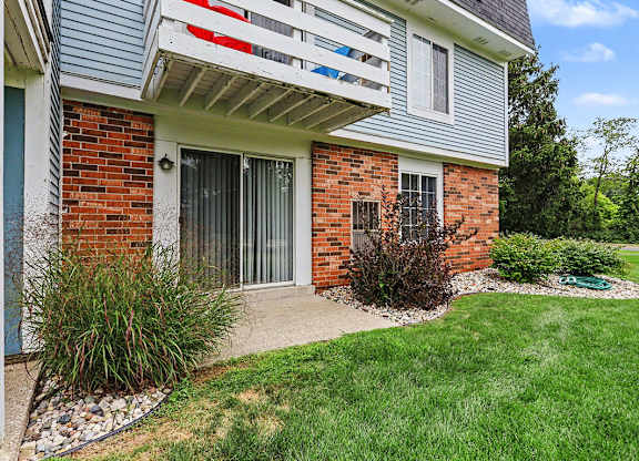 A building with a red brick wall and a white patio at Walnut Trail Apartments, Michigan