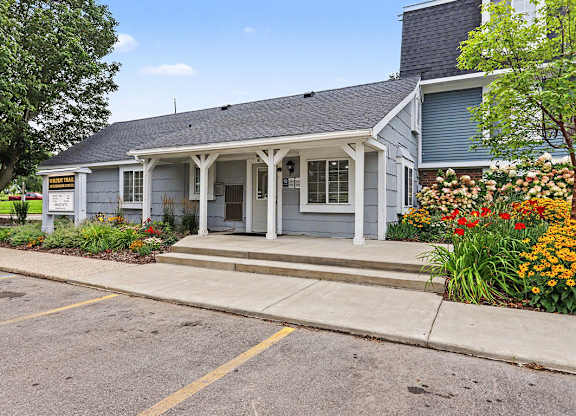 A leasing office with a porch and a sign on the front at Walnut Trail Apartments, Michigan