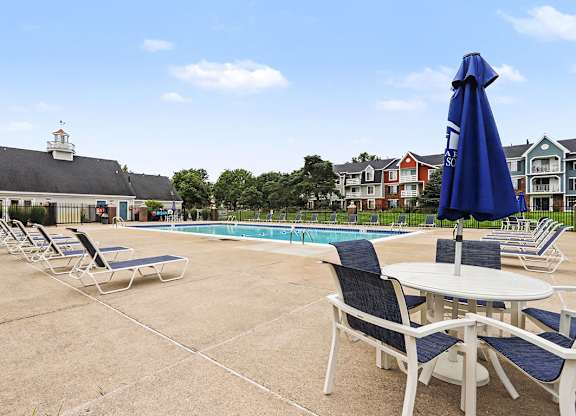 A poolside area with chairs and tables is shown at Walnut Trail Apartments, Michigan
