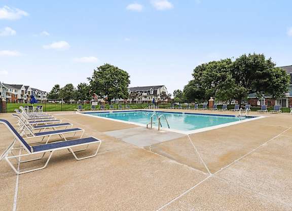 A pool with sun loungers and a blue sky in the background at Walnut Trail Apartments, Michigan