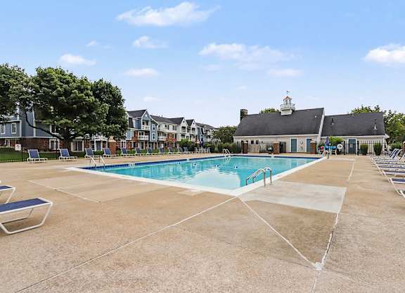 A large swimming pool surrounded by lounge chairs and a building in the background at Walnut Trail Apartments, Michigan