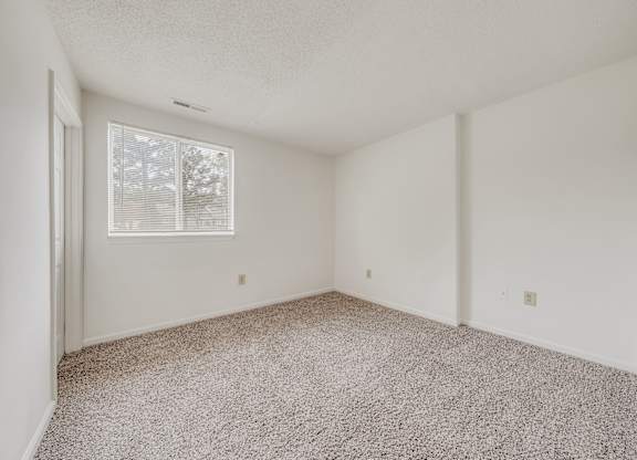 A room with a carpeted floor and a window with blinds at WaterFront Apartments, Virginia Beach, 23453