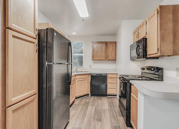 A kitchen with wooden cabinets and black appliances at WaterFront Apartments, Virginia Beach, 23453
