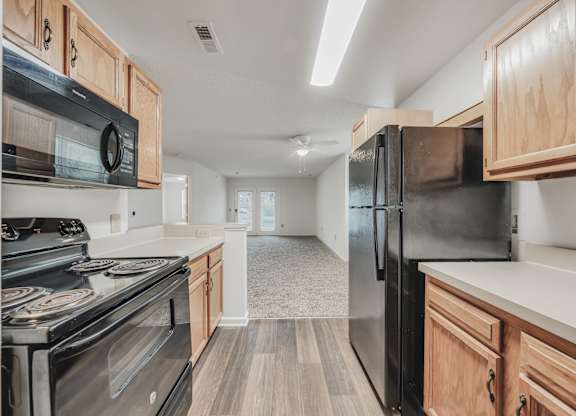 A kitchen with black appliances and wooden cabinets at WaterFront Apartments, Virginia Beach, 23453