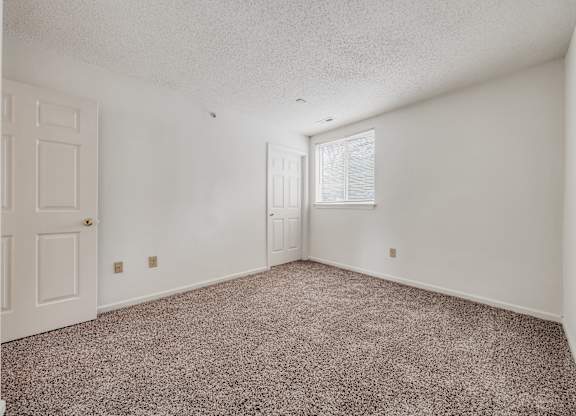A room with a carpeted floor and a door on the left side at WaterFront Apartments, Virginia Beach, 23453
