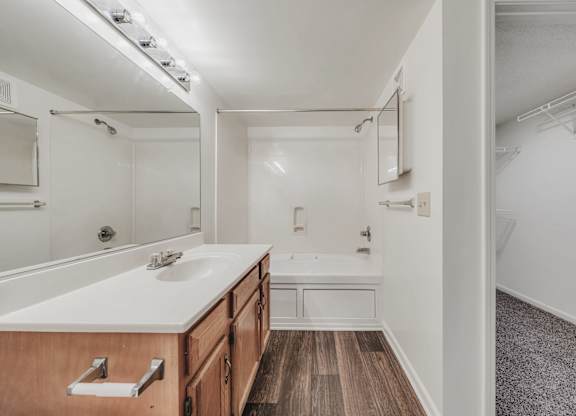 A bathroom with a wooden vanity and a white countertop at WaterFront Apartments, Virginia Beach, 23453