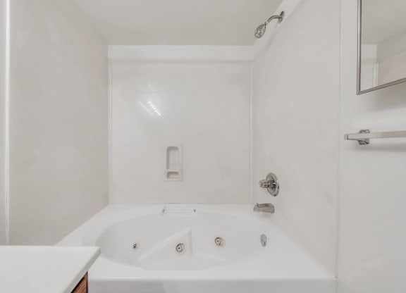 A white bathroom with a tub and a mirror at WaterFront Apartments, Virginia Beach, 23453