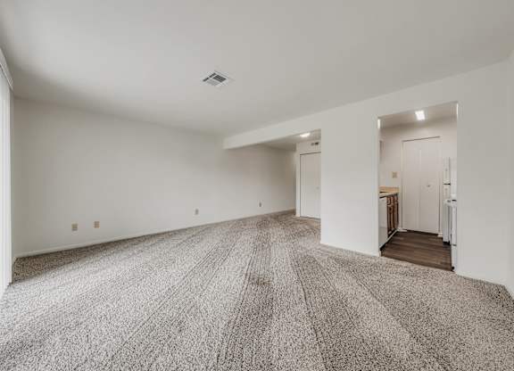 A large, empty room with a carpeted floor and white walls at WaterFront Apartments, Virginia Beach, 23453