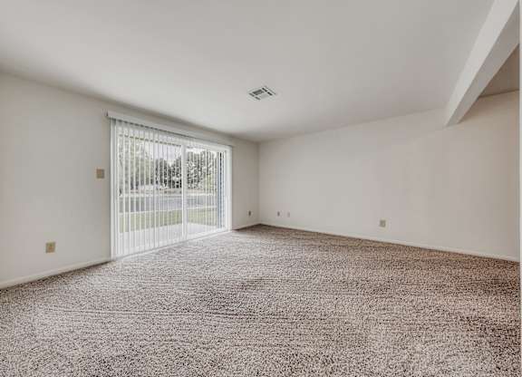 A room with a carpeted floor and a sliding glass door at WaterFront Apartments, Virginia Beach, 23453