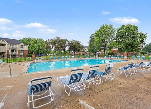 A pool with chairs and trees surrounding it at Waverly Park Apartments, Lansing