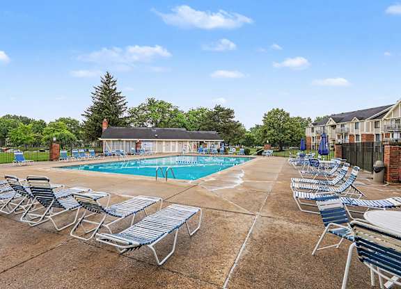 A pool surrounded by chairs and a large sundeck at Waverly Park Apartments, Lansing
