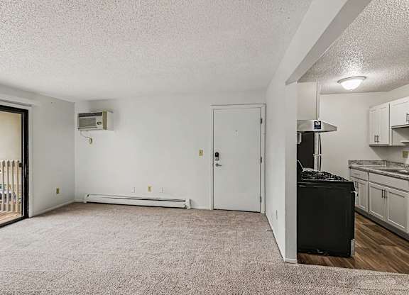 A living room with sliding glass doors to a balcony and an upgraded kitchen at Waverly Park Apartments, Lansing