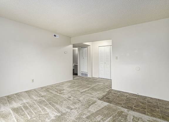 A living and dining room with a carpeted floor at West Wind Apartments in Fort Wayne, IN