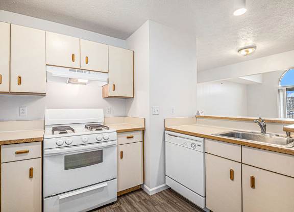 A kitchen with white appliances and wooden cabinets at West Hampton Park Apartments in Elkhorn, NE 68022