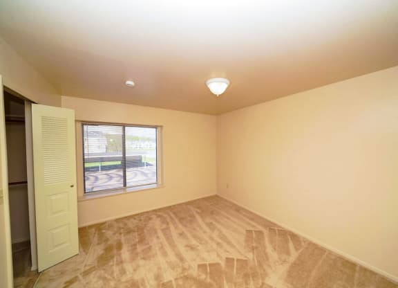 bedroom with a large window and a walk-in closet at Windmill Lakes Apartments, Holland, 49424