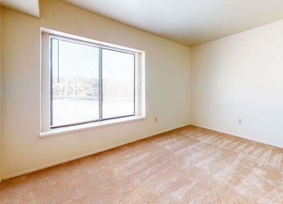 bedroom with a large window and carpeting at Windmill Lakes Apartments, Holland, 49424