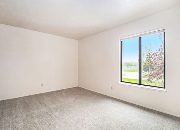 bedroom with a large window and carpeting at Wingate Apartments, Kentwood, 49512