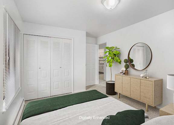 An upgraded bedroom with a green bedspread and a large closet at Wingate Apartments, Michigan