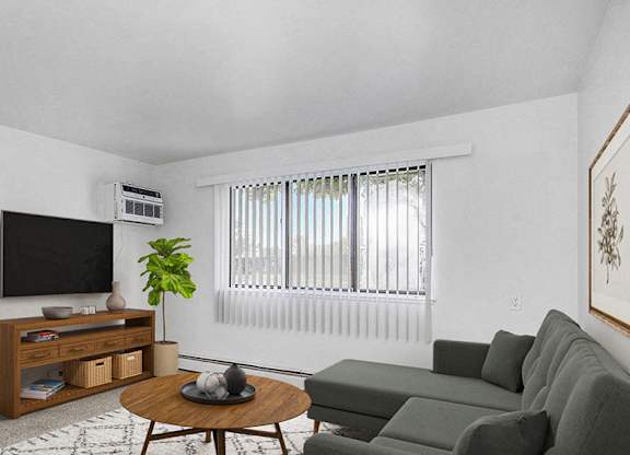 A garden style living room with a grey couch, a wooden coffee table, and a television at Wingate Apartments, Michigan