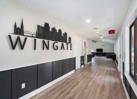A hallway to the leasing office with a sign on the wall at Wingate Apartments, Kentwood
