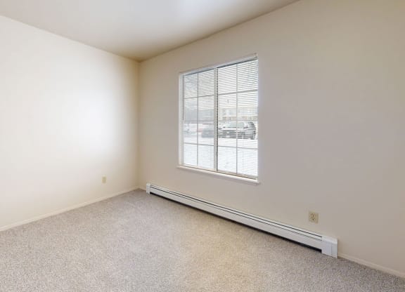 a bedroom with a large window and plush carpeting  at Wood Creek Apartments, Wisconsin, 53144
