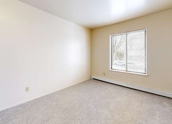 A large bedroom with a window and carpeted floor at Wood Creek Apartments, Kenosha, WI, 53144