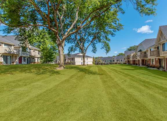 A tree stands in the middle of a grassy courtyard between apartment buildings at Wood Creek Apartments, Wisconsin