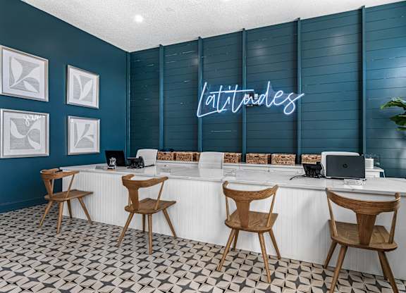 a blue and white lobby with chairs and a desk with a laptop at Latitudes Apartments, Indianapolis, IN