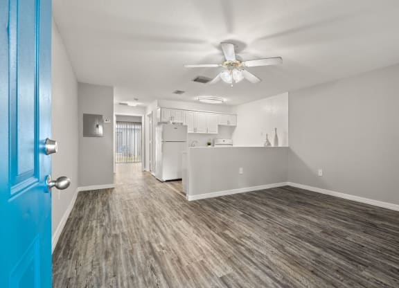 the living room and kitchen of an apartment with a blue door