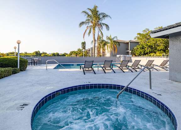 A hot tub with a blue tiled edge sits in the middle of a patio.
